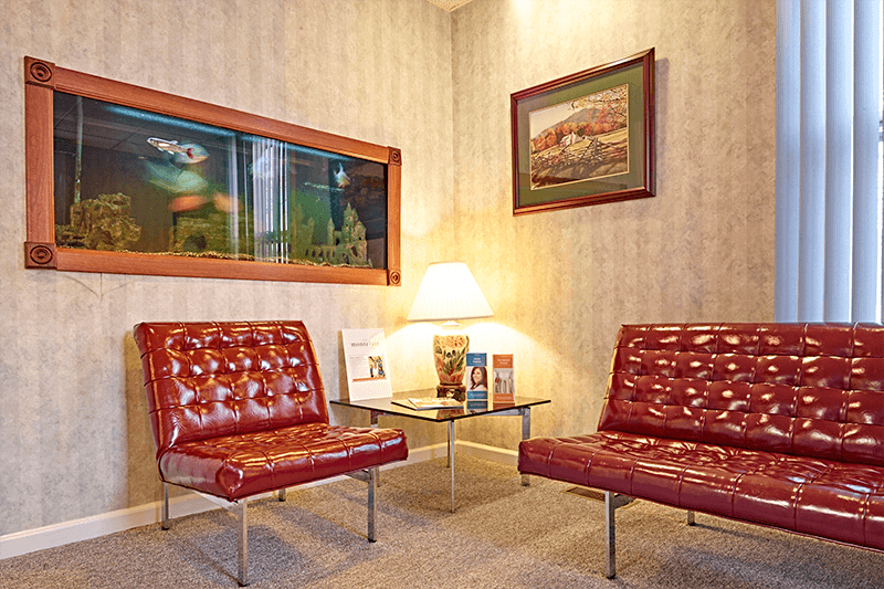 waiting area with red leather couches, glass table and Fish tank