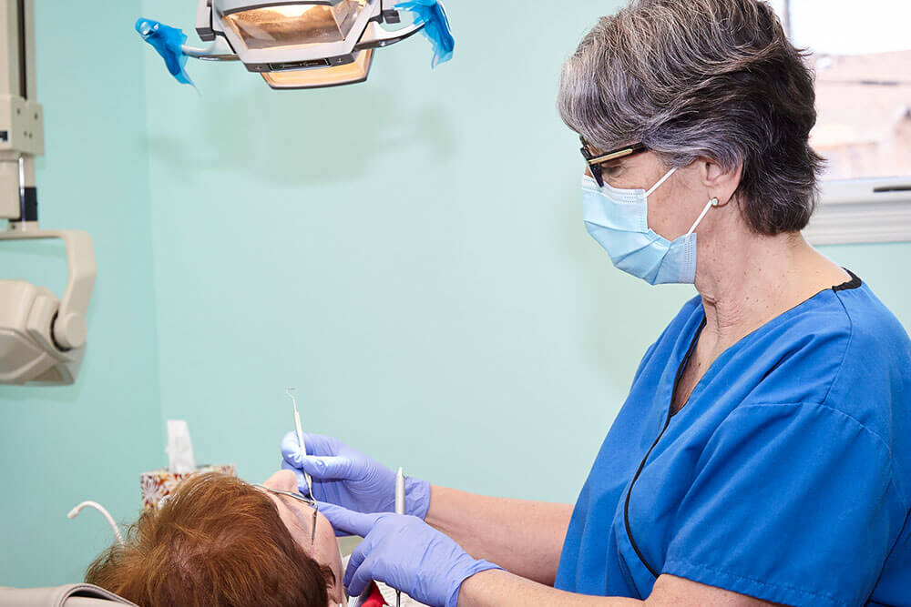 female dentist examining female patient's teeth
